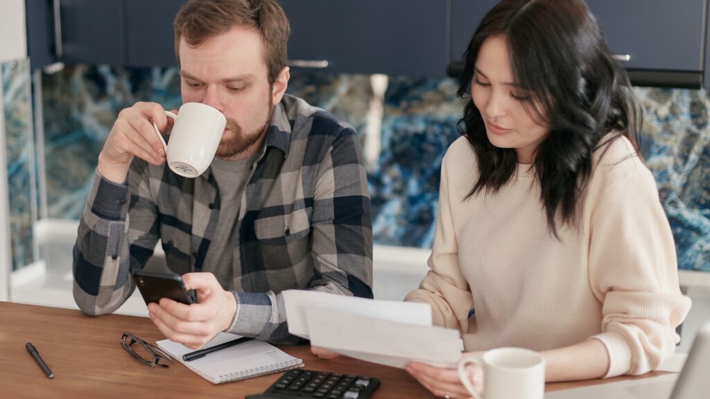 This image shows a couple sitting at the table with a morning coffee reviewing their budget.